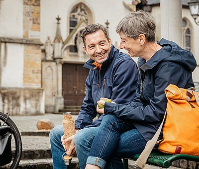 Zwei Personen sitzen an einer Kirche 